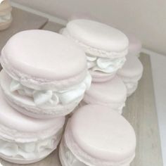 a pile of white macaroons sitting on top of a wooden floor next to each other