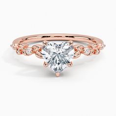 a rose gold engagement ring with a heart shaped diamond in the center and side stones