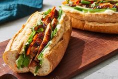 two sandwiches sitting on top of a wooden cutting board