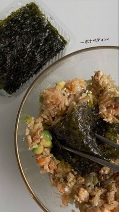 a plate with rice and vegetables on it next to a plastic container filled with seaweed