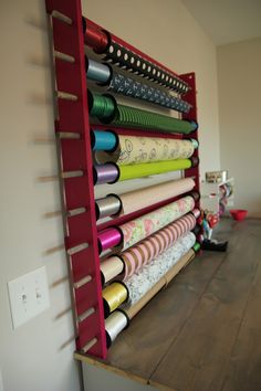 a red rack holding many different types of sewing threads on top of a wooden table