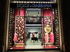 the entrance to dolce and garbana store with red curtains, gold decorations and mannequins