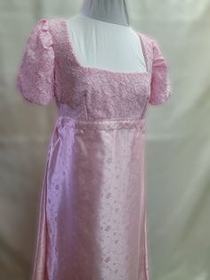 This dress has free standard shipping included!  Standard shipping Air Mail, no tracking.  If you would like Express Post or place by place tracking, please contact us, and we can set that up for you!   We offer a basic Regency styled gown, with the empire waist and short puffed sleeves.  This stunning dress has a light pink top with a little bit of sparkle woven in. Top and sleeves are lined.  Skirt is made from a light pink satin brocade with a dainty floral design.    *This gown ties at the b Fitted Gown With Square Neck, Fitted Gown With Square Neck For Formal Events, Fitted Gown With Square Neck For Formal Occasions, Fitted Formal Gown With Square Neck, Pink Fitted Lace Gown, Empire Waist Fitted Evening Dress, Fitted Feminine Maxi Dress With Empire Waist, Feminine Fitted Empire Waist Maxi Dress, Pink Fitted Full-length Evening Dress