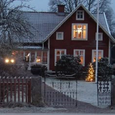 a red house is lit up with christmas lights in the front yard and on the other side