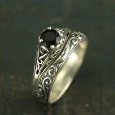 a silver ring with a black stone in the center and filigrees on it