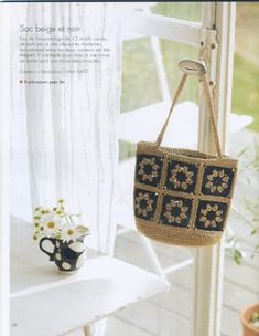 a purse hanging from the side of a window next to a vase with flowers in it