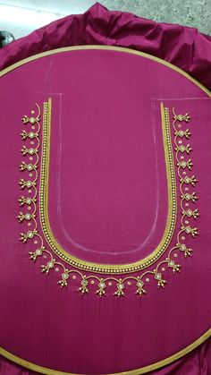 a pink pillow with gold embroidery on the front and side, sitting on top of a table