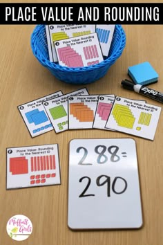 place value and rounding cards on a table next to a blue basket with markers in it