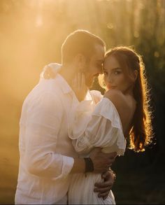 a man and woman embracing each other in front of the sun shining down on them