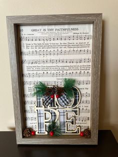 an old sheet music frame with the word hope in it and pine cones on top