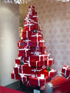 a red car parked next to a christmas tree with presents on it's roof