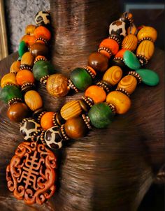 This stunning triple strand oversized beaded statement necklace will look fabulous paired with animal prints or authentic African prints. Components include zebu bone, wood, African recycled glass, quartz teardrop beads, copper daisy spacers, dark brown wood rondelles, bronze rhinestone rondelles, hand painted African glass beads, an Ethiopian copper bead and gold tone tribal spacers. A hand carved rust colored Asian pendant is the focal point which measures 2.5" x 2.5". I would describe this as a medium weight, but please remember that weight is subjective. Adjusts from 17-20" and I can add more links if requested. Silver tone hardware and a lobster claw clasp. From the Atelier of Kat Kouture. Traditional Brown Multi-strand Necklaces, Eclectic Handmade Brown Jewelry, Rocker Chic Accessories, Necklace African, Unique Pendant Necklace, Statement Bib Necklace, Chest Piece, African Prints, Mermaid Necklace