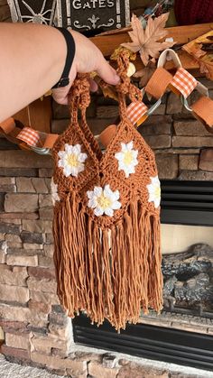 a person is holding up a crocheted purse with flowers on the front and sides