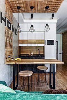 a kitchen with wood floors and white cabinets, hanging lights over the island counter top