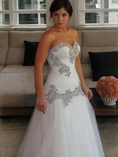 a woman in a white wedding dress standing next to a couch