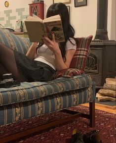 a woman sitting on a couch reading a book