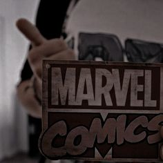 a person holding up a wooden sign that says,'marvel comics '