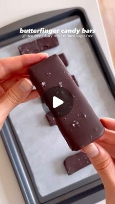 a person holding an ice cream bar in front of a tray with chocolate bars on it