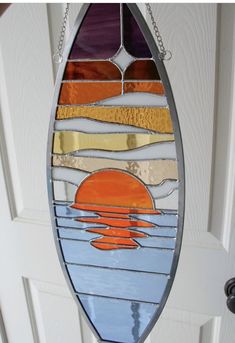 a stained glass sun catcher hanging from a white door with the sunset reflected in it