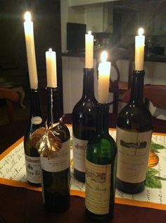 several wine bottles with lit candles sitting on a table