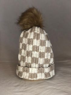 a knitted hat with a pom - pom sits on a gray background