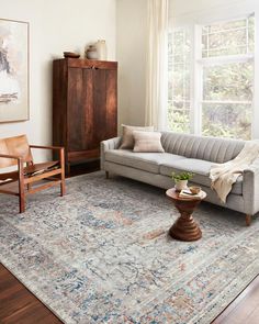 a living room with a couch, chair and rug on the floor in front of a window