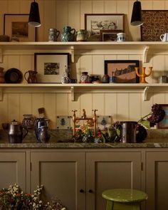 a kitchen with shelves filled with pots, pans and vases on top of it