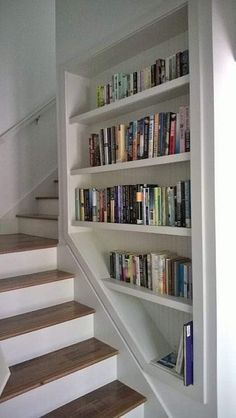 there are many books on the shelves next to the stairs