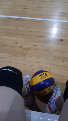 two people are sitting on the floor with their feet in front of a volleyball ball