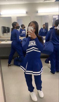 a woman taking a selfie in front of a mirror wearing a cheerleader outfit