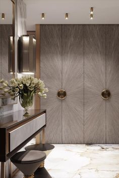 an elegant bathroom with marble floors and gold accents on the walls, along with two vases filled with flowers