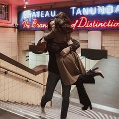 two women are walking up an escalator in a subway station, one is holding the other