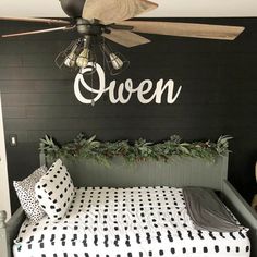 a bed with black and white sheets underneath a ceiling fan that says queen on it