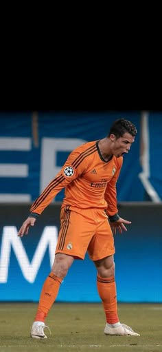 a soccer player in an orange uniform is on the field and ready to kick the ball