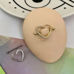 a pair of heart shaped earrings sitting on top of a table next to a plate