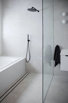 a bathroom with a glass shower door and white tiles on the walls, along with a black towel