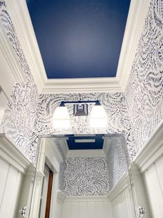 a bathroom with blue and white wallpaper and ceiling light fixture in the mirror area