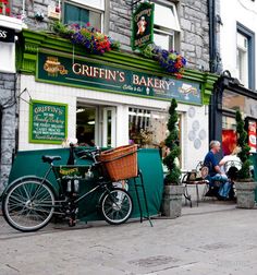 a bicycle parked in front of a green bakery