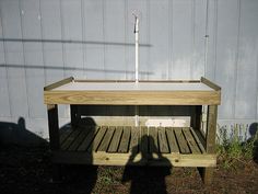 a wooden bench sitting in front of a white wall with an umbrella on it's side