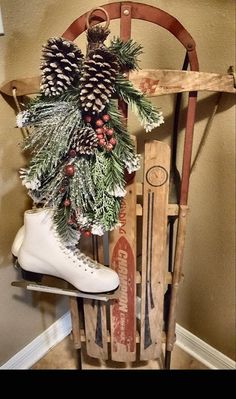 an old sled with pine cones, evergreen and skis on it sitting next to a wall