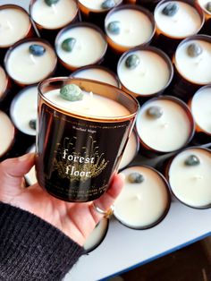 a person holding a candle in front of rows of lit candles with the words forest house on them