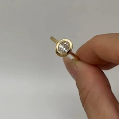 a person holding a gold ring with a diamond in it's center, on a white background