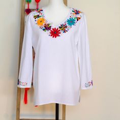 White Bohemian Embroidered Tunic Top, Bohemian White Embroidered Tunic Top, Multicolor Embroidered Long Sleeve Beach Top, Multicolor Embroidery Long Sleeve Vacation Tops, Folk Style Multicolor Vacation Tops, Folk Style Embroidered Peasant Top For Vacation, Peasant Floral Embroidered Top For Beach, Traditional Cotton Tunic With Embroidered Neckline, Long Sleeve Blouse With Multicolor Embroidery For Vacation