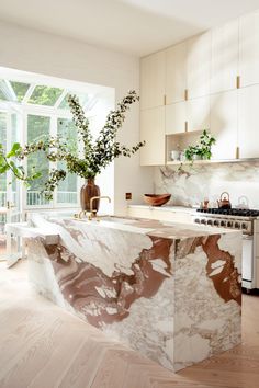 a kitchen with marble counter tops and white cabinets, along with an island in the middle