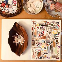 an open book on a table next to plates and bowls with paper cutouts in them