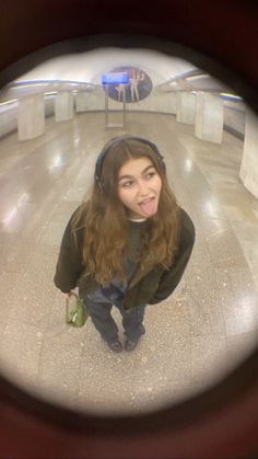 a girl with headphones is looking through a fisheye lens