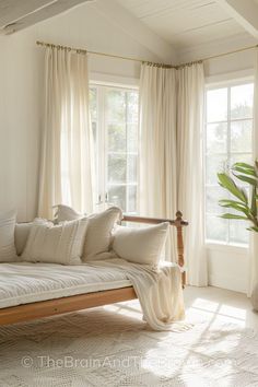 a white couch sitting in front of a window next to a potted palm tree