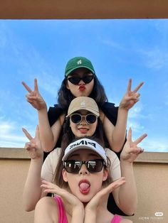 three girls wearing sunglasses and hats are posing for the camera with their hands in the air