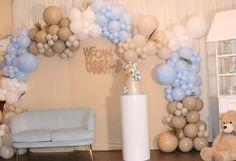 a balloon arch is decorated with balloons and a teddy bear sitting on the floor in front of it