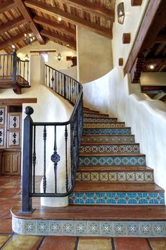 a stair case with blue and green tiles on the bottom, and wooden handrails